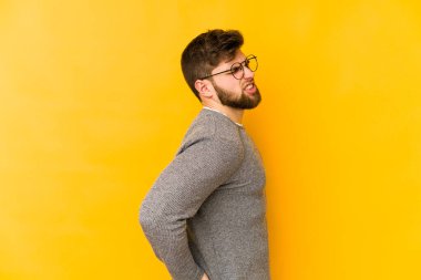 Sarı arka planda izole edilmiş beyaz bir adam sırt ağrısı çekiyor..