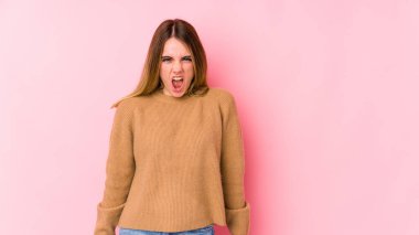 Pembe arka planda izole edilmiş genç beyaz kadın çok kızgın, öfkeli, hayal kırıklığına uğramış.
