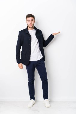 Tam gövdeli, beyaz tenli, izole edilmiş genç bir adam, avuç içinde fotokopi alanı tutuyor..