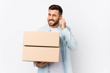 Genç beyaz adam yeni evine taşınıyor. Elleriyle kulaklarını kapatıyor..