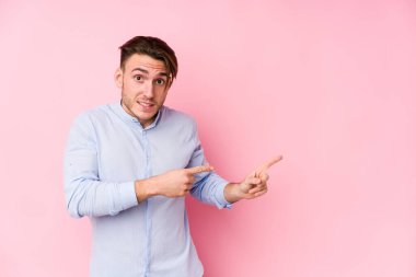 Pembe arka planda poz veren beyaz genç bir adam işaret parmağıyla fotokopi çekilen yeri işaret ederek şok oldu..