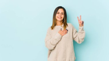 Mavi arka planda izole edilmiş genç bir kadın yemin ediyor, elini göğsüne koyuyor..