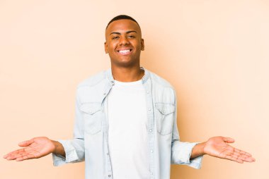 Bej arka planda izole edilmiş genç latin adam hoş bir ifade sergiliyor..