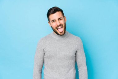 Mavi arka planda genç beyaz bir adam izole edilmiş komik ve dost canlısı bir dil kullanıyor..