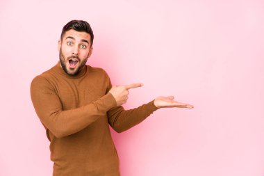 Pembe arka planda genç beyaz bir adam. Palmiye üzerinde bir fotokopi alanı tuttuğu için heyecanlı..