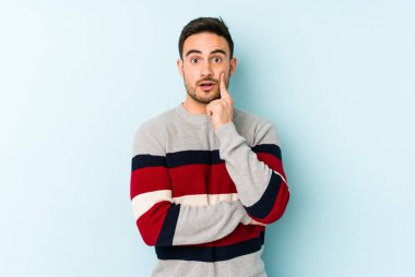 Kafkasyalı genç adam mavi arka planda izole edildi. Harika bir fikri var, yaratıcılık kavramı..