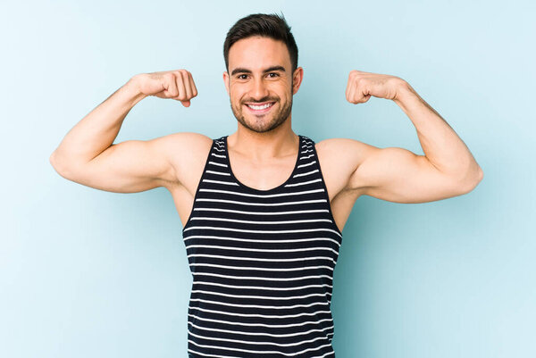 Young caucasian man isolated on blue background showing strength gesture with arms, symbol of feminine power