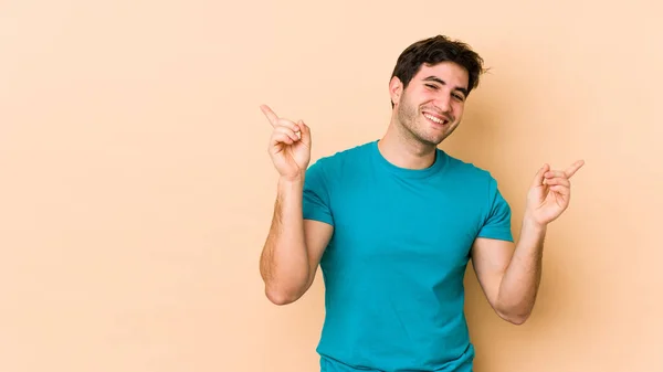 Jeune Homme Isolé Sur Fond Beige Pointant Vers Différents Espaces — Photo