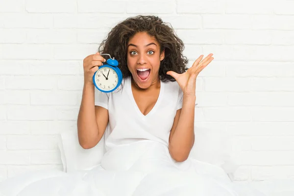 Young African American Woman Sitting Bed Holding Alarm Clock Celebrating — Stock Photo, Image