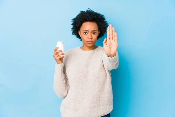 中年非洲妇女拿着一个维生素瓶站在那里 伸出的手显示出停止的迹象 阻止了你 — 图库照片