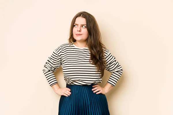 Young curvy woman confused, feels doubtful and unsure.