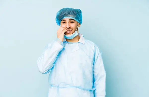 Jonge Arabische Chirurg Geïsoleerd Tegen Een Blauwe Achtergrond Bijtende Vingernagels — Stockfoto