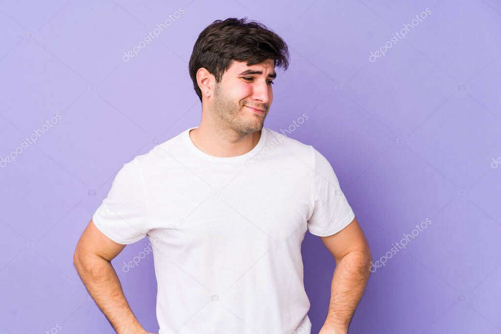 Young man isolated on purple background confused, feels doubtful and unsure.