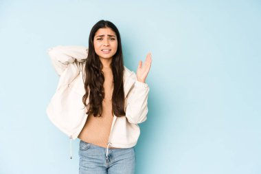 Mavi arka plandaki genç Hintli kadın öfkeyle bağırıyor..