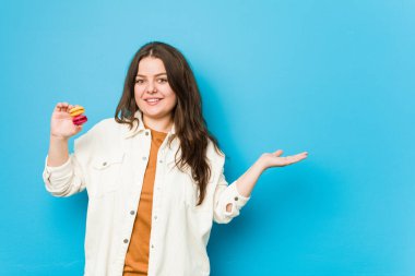 Elinde kurabiyelerle avucunun içinde fotokopi çeken ve belinde başka bir el tutan kavisli genç bir kadın..