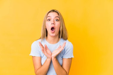 Sarışın, beyaz bir kadın. Sarı arka planda izole edilmiş. Şaşırmış ve şok olmuş..
