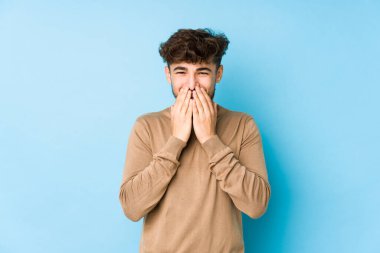 Genç Arap bir adam bir şeye gülüyor, elleriyle ağzını kapatıyor..