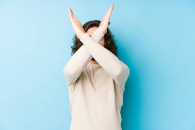 Uzun saçlı genç adam mavi arka planda izole edilmiş iki kolu çapraz tutuyor, inkar kavramı..