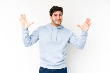Beyaz arka planda izole genç bir adam hoş bir sürprizle karşılaşıyor, heyecanlı ve el kaldırıyor..