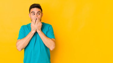 Kafkasyalı genç adam, sarı fırında izole edilmiş. Düşünceli bir şekilde, ağzını eliyle kapatan bir fotokopi odasına bakıyor..