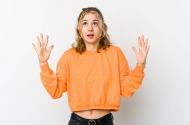 Beyaz arka plandaki genç beyaz kadın gökyüzüne haykırıyor, yukarı bakıyor, hayal kırıklığına uğramış..