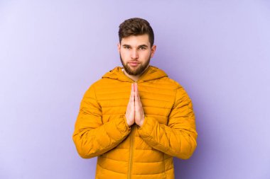 Mor arka planda izole edilmiş genç adam dua ediyor, bağlılık gösteriyor, dindar biri ilahi ilham arıyor..