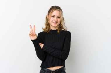 Beyaz arka plandaki genç beyaz kadın iki numarayı parmaklarıyla gösteriyor..