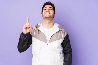 Mor arka planda izole genç adam iki ön parmağı da boş bir alan gösteriyor..