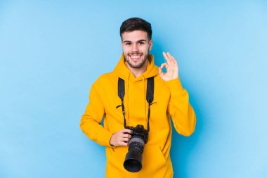 Kafkasyalı genç fotoğrafçı neşeli ve kendinden emin bir şekilde iyi bir jest yapıyor..