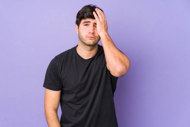 Mor arka planda soyutlanmış genç bir adam yorgun ve uykulu. Elini başının üstünde tutuyor..