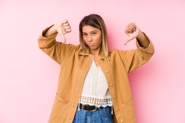 Kafkasyalı genç bir kadın soyutlanmış poz veriyor başparmağını aşağı gösteriyor ve hoşlanmadığını ifade ediyor..