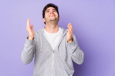 Mor arka planda izole edilmiş genç bir adam neşeli bir şekilde gülüyor. Mutluluk kavramı.