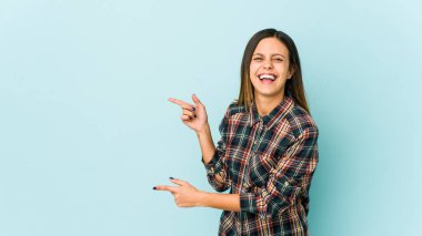 Mavi arka planda izole edilmiş genç bir kadın işaret parmaklarıyla fotokopi alanını işaret ederek heyecan ve arzusunu ifade ediyor..