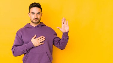 Kafkasyalı genç adam sarı fırında izole edilmiş yemin ediyor, elini göğsüne koyuyor..