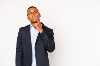 Genç iş adamı beyaz arka planda izole edilmiş şüpheli ve şüpheci bir ifadeyle yana bakıyor..