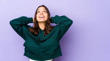 Genç, melez İspanyol kadın kendini soyutlamış, kendinden emin, elleri başının arkasında..