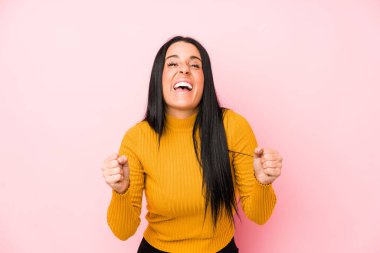 Pembe arka planda izole edilmiş beyaz bir kadın tasasız ve heyecanlı bir şekilde tezahürat yapıyor. Zafer konsepti.