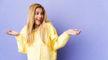 Mor arka planda izole edilmiş genç sarışın kadın neşeli bir şekilde gülüyor. Mutluluk kavramı.