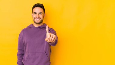 Sarı fırında izole edilmiş genç beyaz bir adam bir numarayı parmağıyla gösteriyor..