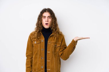 Uzun saçlı adam yalnız poz veriyor. Kopya alanını avucunun içinde tutmaktan etkilenmiş..