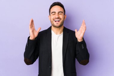 Mor arka planda izole olmuş genç beyaz adam yüksek sesle gülüyor elini göğsüne koyuyor..