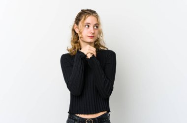 Beyaz sırtlı genç beyaz kadın ellerini çenesinin altında tutuyor, mutlu bir şekilde yan tarafa bakıyor..