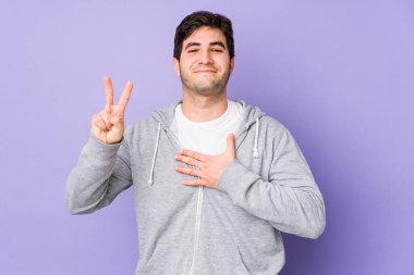 Mor arka planda izole edilmiş genç adam yemin ediyor, elini göğsüne koyuyor..