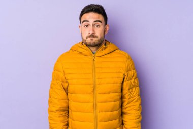 Mor arka planda izole genç beyaz adam omuzlarını silker ve gözleri açık kalır..