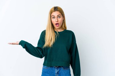 Beyaz arka planda izole edilmiş genç sarışın kadın, avuç içinde kopya alanı tutmaktan etkilenmiş..