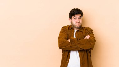 Bej arka planda izole edilmiş genç adamın yanakları şişiyor, yorgun bir ifadesi var. Yüz ifadesi kavramı.