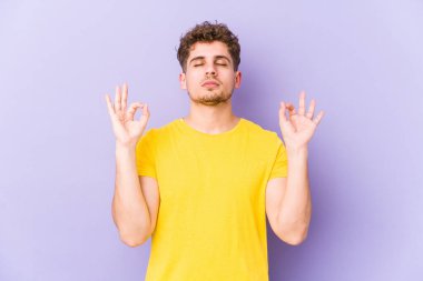 Sarışın, kıvırcık saçlı, beyaz tenli genç adam sıkı çalışma gününden sonra dinleniyor. Yoga yapıyor..