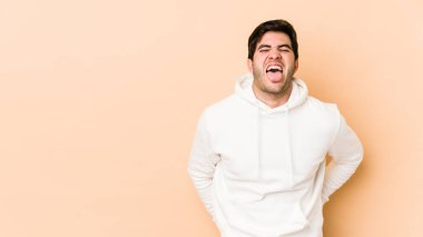 Bej arka planda izole edilmiş genç bir adam. Komik ve dost canlısı bir dil uzatıyor..