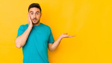 Sarı fırında izole edilmiş genç beyaz adam, avuç içinin fotokopi alanını elinde tutmaktan etkilendi..