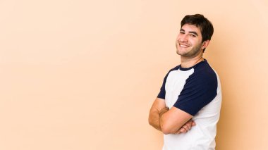 Bej arka planda izole edilmiş genç adam mutlu, güler yüzlü ve neşeli.